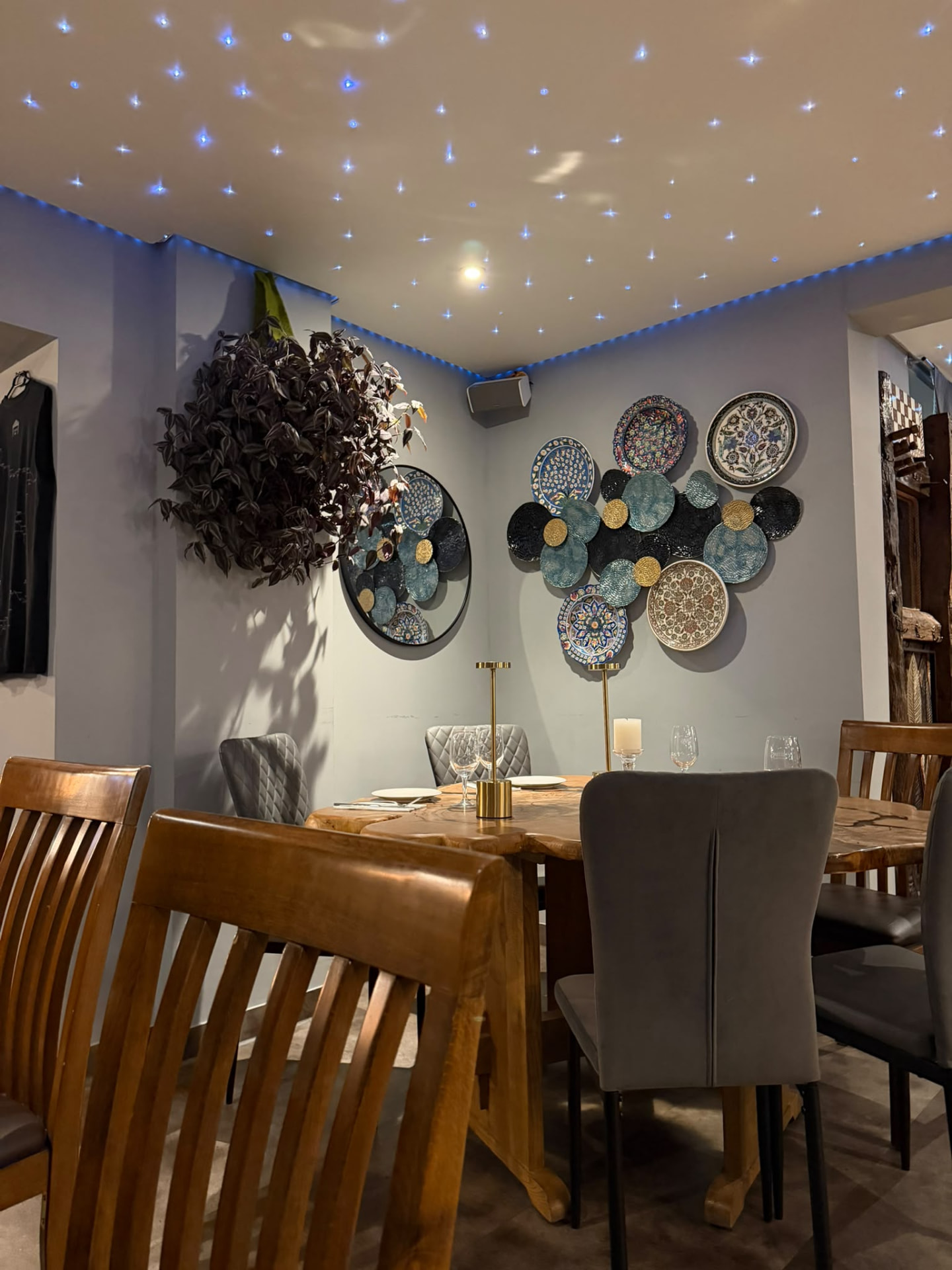 Gedeckter Tisch mit handbemalten Keramikteller an der Wand im Trüffel Fine Dining